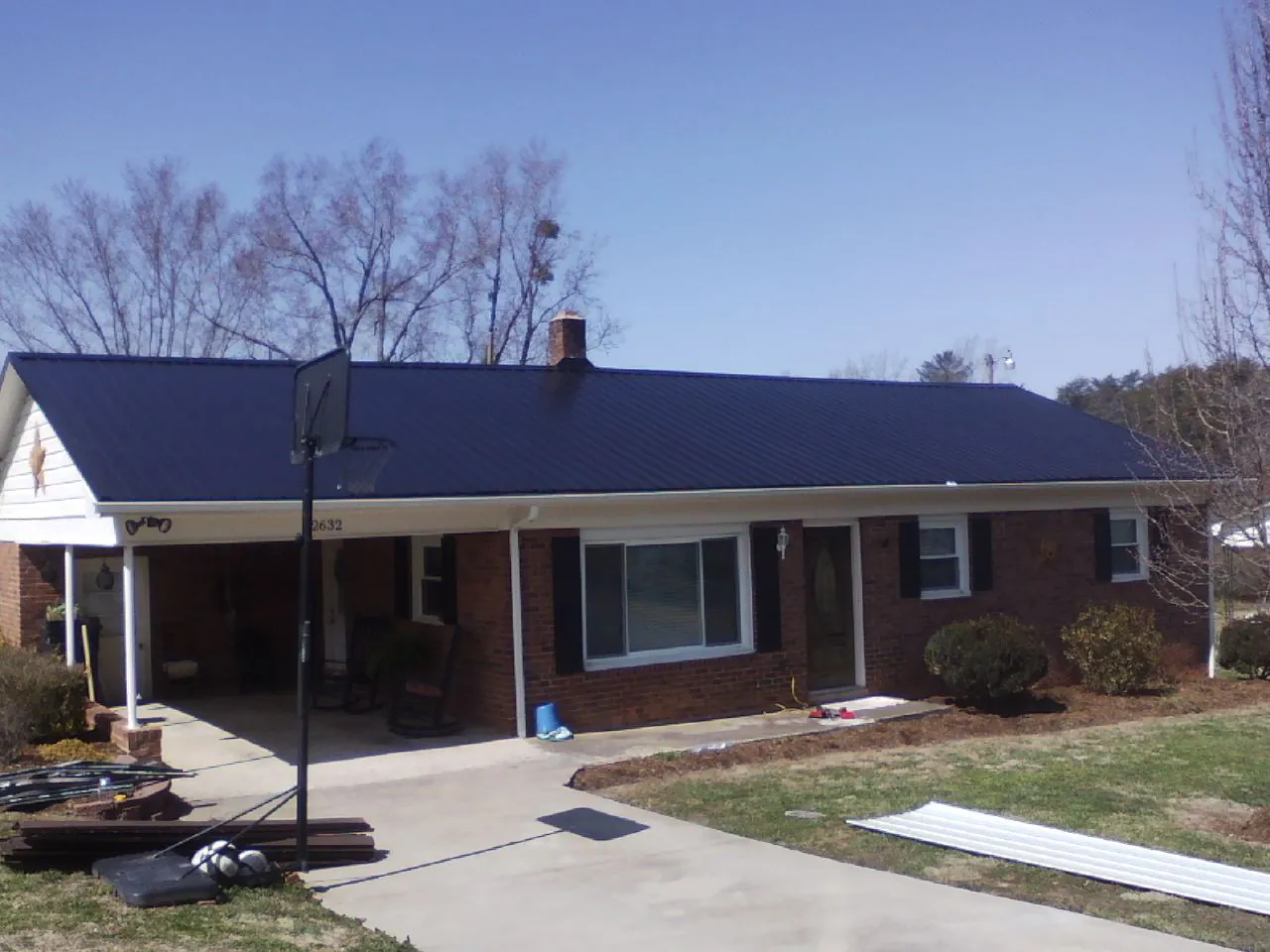 Finished dark blue metal roof on a brick ranch with a carport in Lusby