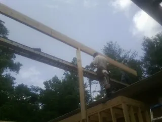 Carpenter setting a ridge beam over a new addition frame — Ice Dam Removal by Roofing Brothers in Lusby