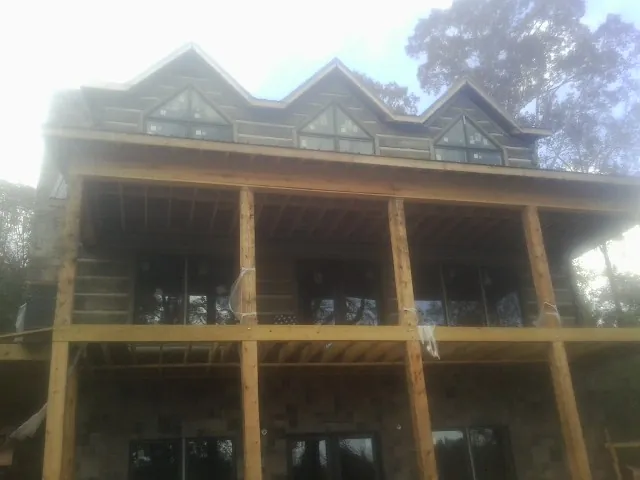 Dormers and porch framing on a large log home under construction — Roof Coating work by our crew in Lusby