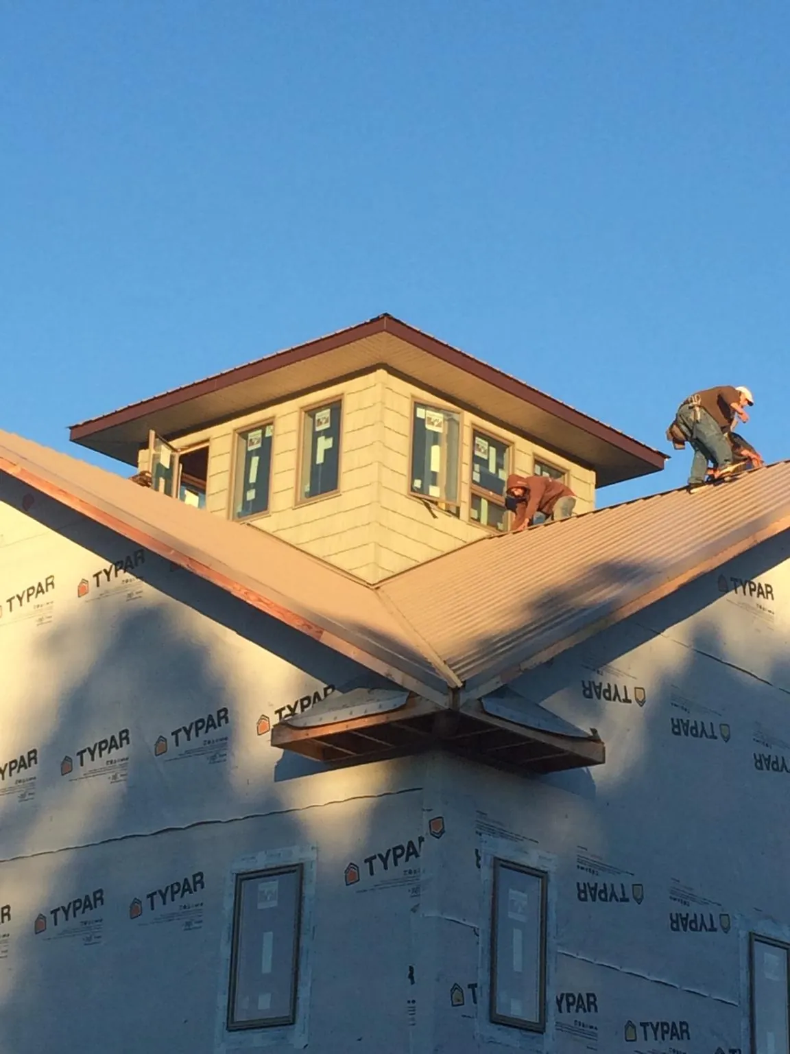 Roofers working around a rooftop cupola on a new metal roof at sunset — Roof Waterproofing in Lusby by Roofing Brothers